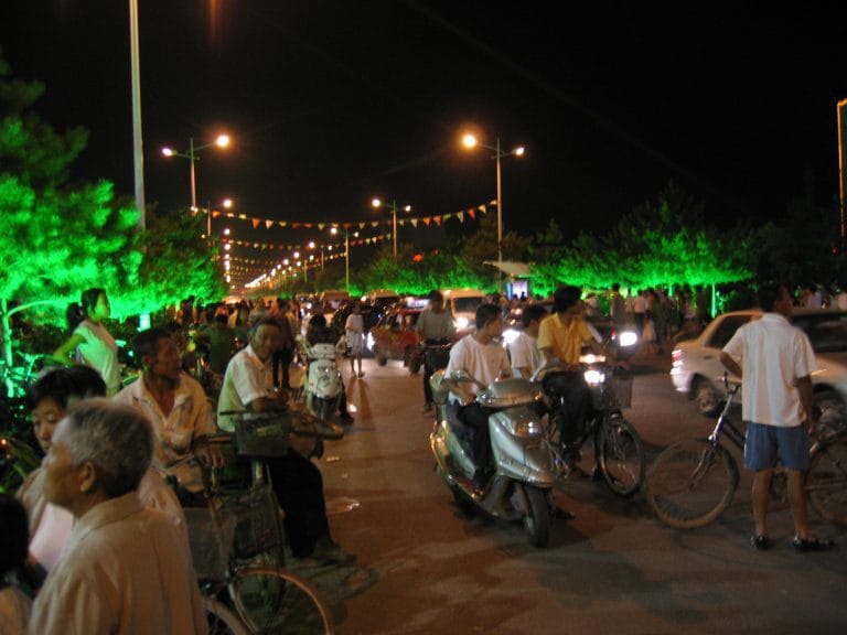 Verlichte avondstraat in Hohhot met kleurrijke slingers en voetgangers in de zomeravond