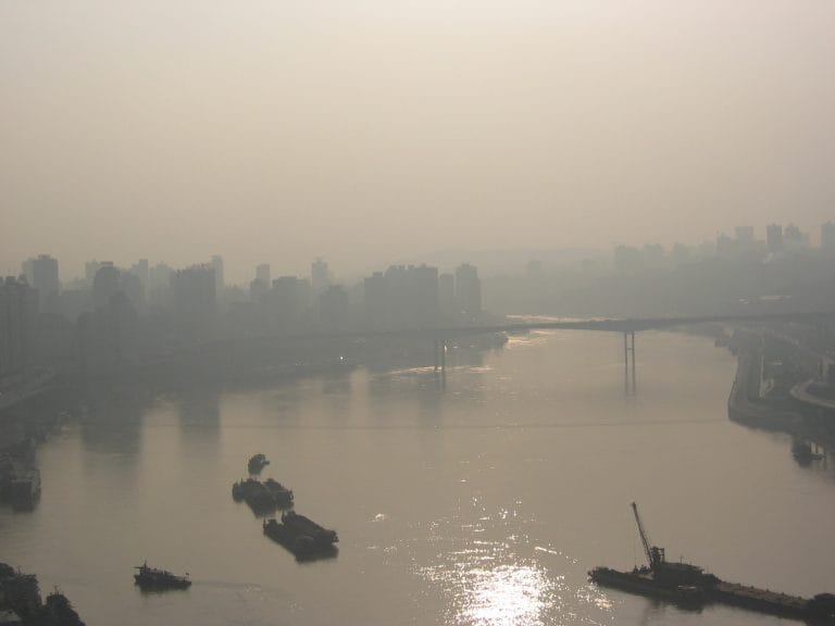 Stadshorizon van Chongqing nauwelijks zichtbaar door dikke bruine smog die de hele stad bedekt