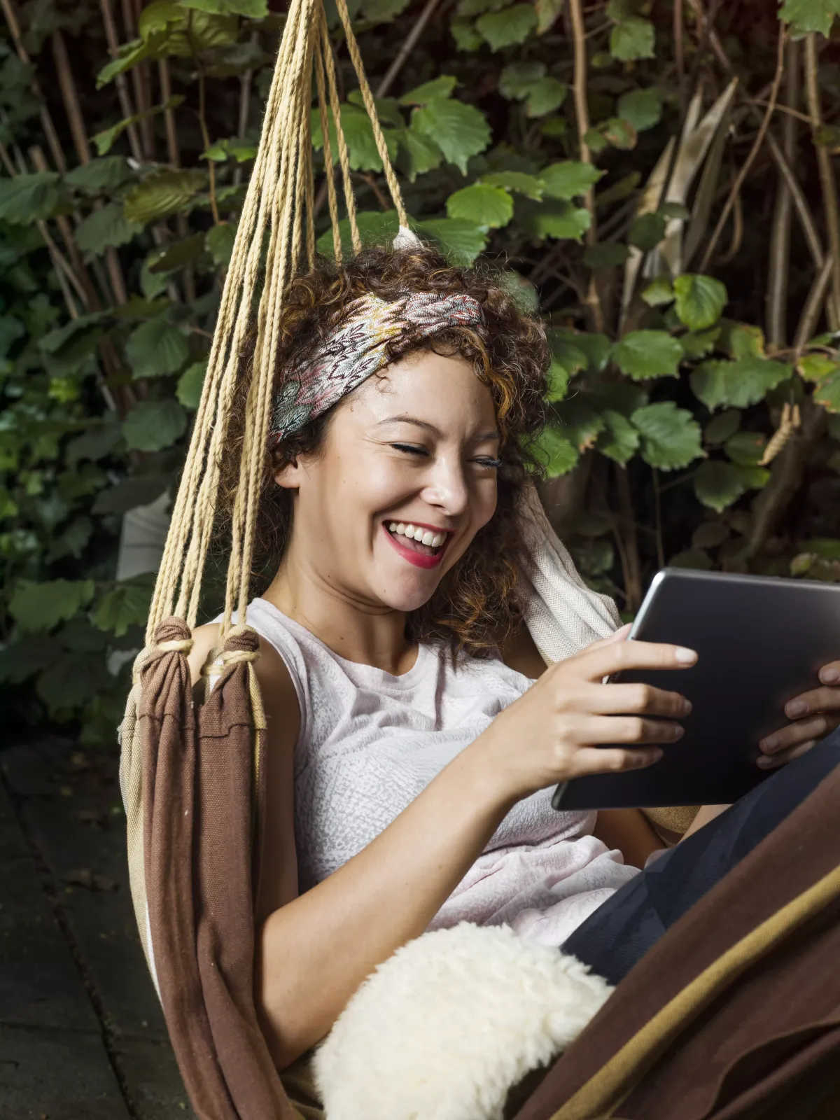 Vrouw aan het ontspannen met haar tablet in een hangmat
