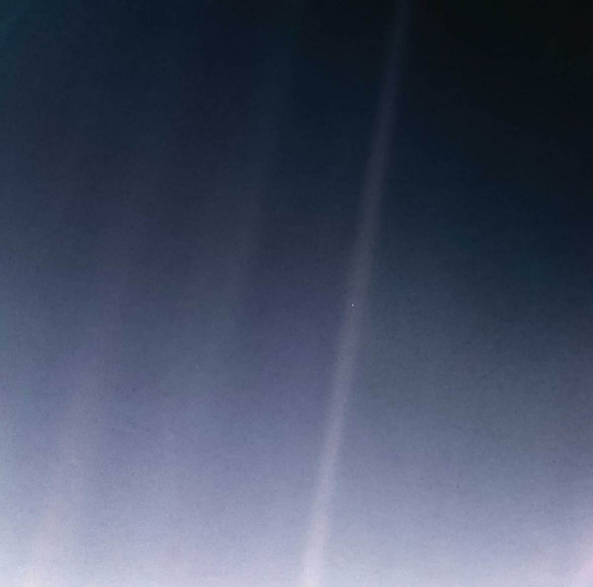 Earth appears as a tiny speck of light suspended in a sunbeam against the vastness of space.